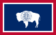 The flag of Wyoming. A dark blue background, bordered by a white outline and then a red outline. In the center is a white buffalo in profile, with the state seal of Wyoming.